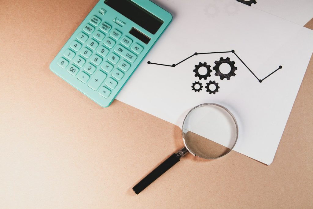 Calculator, magnifying glass, and chart with gears on paper